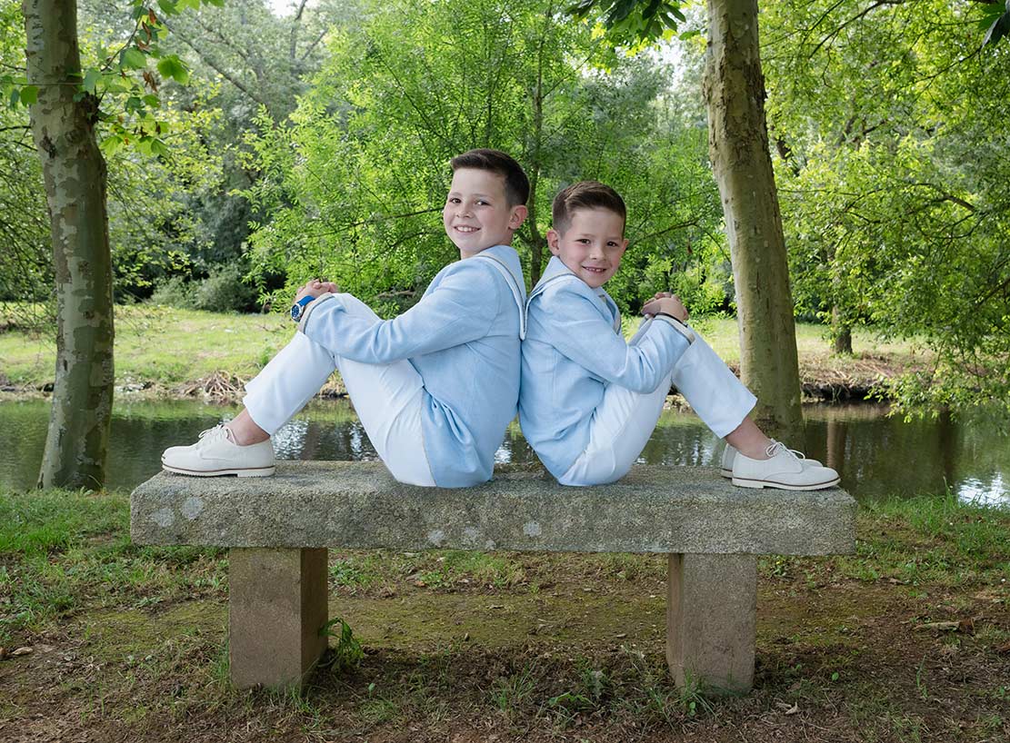 Dos niños vestidos de comunión posando en un banco junto al río en Melide – Sanoguera Fotografía