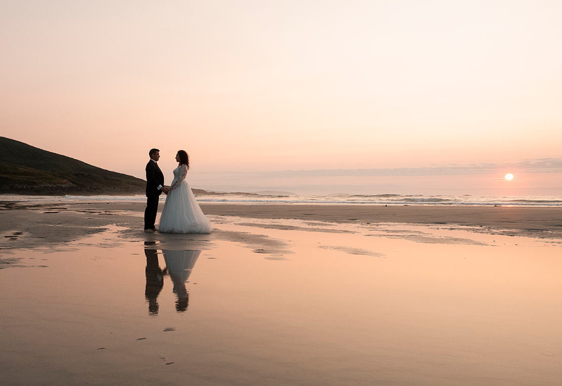 Bodas en verano, fotos al atardecer en Galicia Pareja de novios en la playa al atardecer durante su reportaje de boda en Galicia
