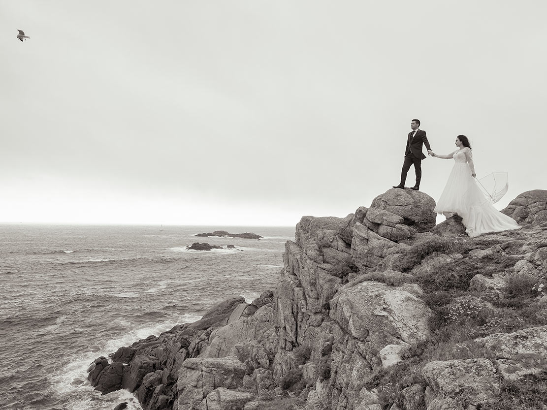 Pareja de novios en acantilados de A Coruña durante su reportaje de boda con vistas al mar
